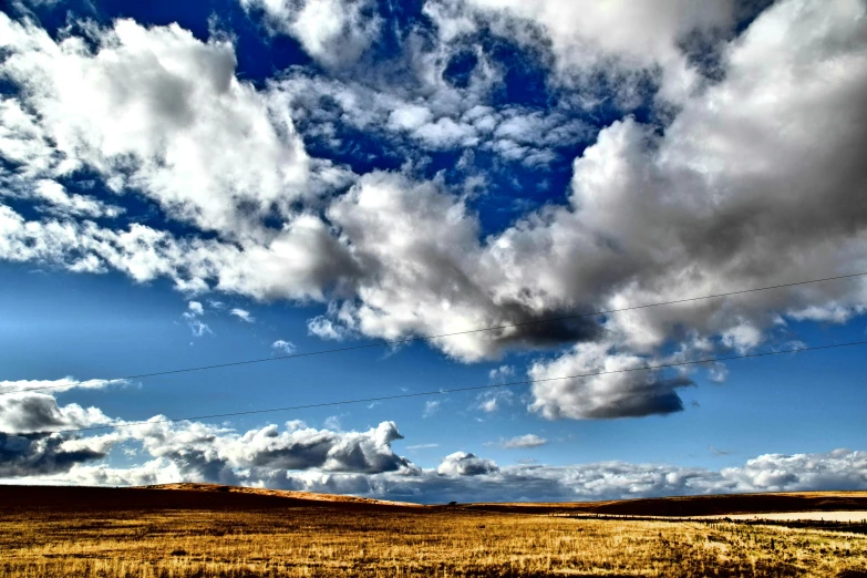 a red fire hydrant sitting in the middle of a field, by Tom Carapic, flickr, land art, layered stratocumulus clouds, yellow and blue, american west scenery, grain”