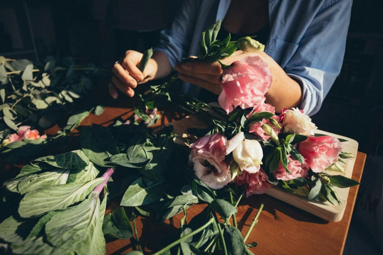 a person sitting at a table with a bunch of flowers, unsplash, arts and crafts movement, laying on roses, lush botany, back towards camera, carefully crafted