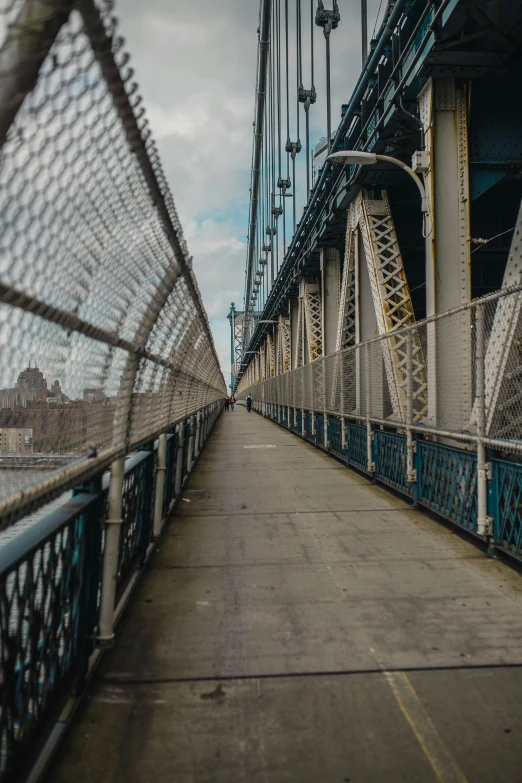 a person walking across a bridge on a cloudy day, inspired by Thomas Struth, unsplash contest winner, graffiti, nyc, nets, wideangle pov closeup, fences