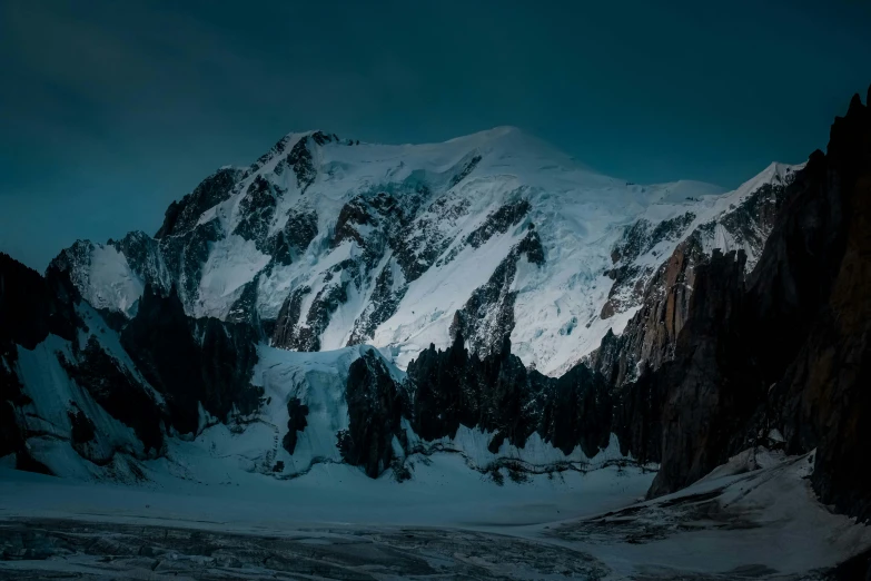 a mountain covered in snow under a blue sky, a matte painting, pexels contest winner, very dark background, chamonix, rugged face, last light