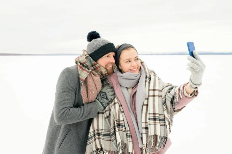 a man and woman taking a selfie in the snow, visual art, gray, grey, rectangle, winter lake setting