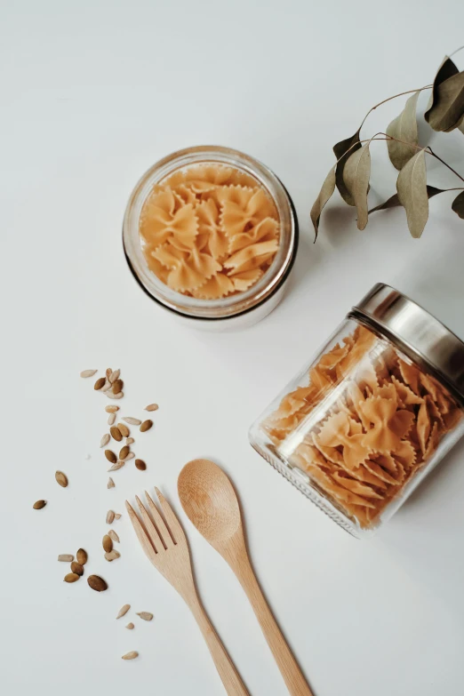 a couple of jars filled with food next to a wooden spoon, pexels contest winner, intricate pasta waves, designer product, gif, full body image