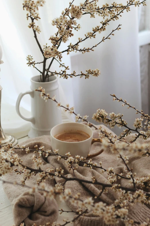 a cup of coffee sitting on top of a table, a still life, inspired by Elsa Bleda, trending on unsplash, romanticism, almond blossom, branches and twigs, brown and cream color scheme, uncropped