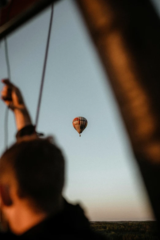 a person taking a picture of a hot air balloon, a picture, by Jacob Toorenvliet, pexels contest winner, over the shoulder, high light on the left, flying shot, summer evening