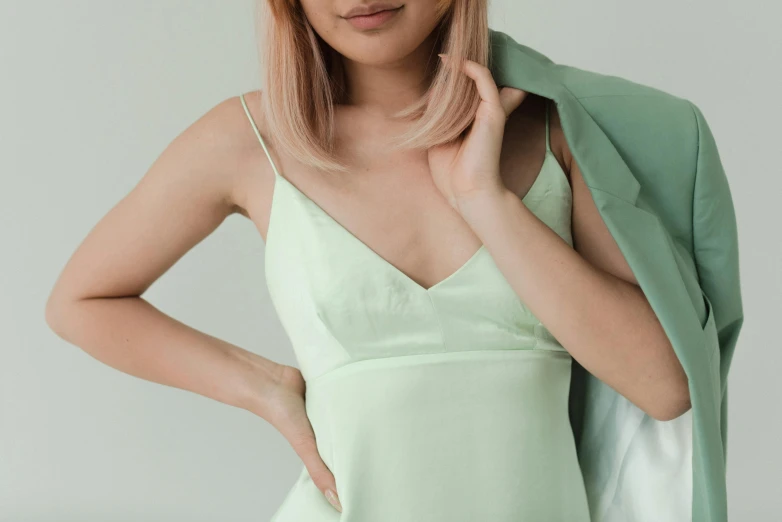 a woman in a green dress posing for a picture, inspired by Ina Wong, trending on pexels, pastel pink skin tone, wearing a camisole, photoshoot for skincare brand, wearing white silk