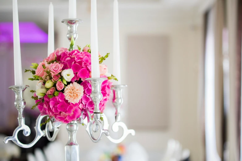 a close up of a candelier with flowers and candles, a cartoon, unsplash, on a white table, vibrant pink, gleaming silver and rich colors, d. i. y. venue