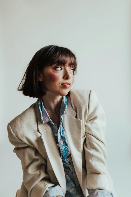 a woman sitting on a chair in a room, an album cover, by Gavin Hamilton, trending on pexels, short brown hair with bangs, wearing a fancy jacket, wearing a linen shirt, headshot profile picture