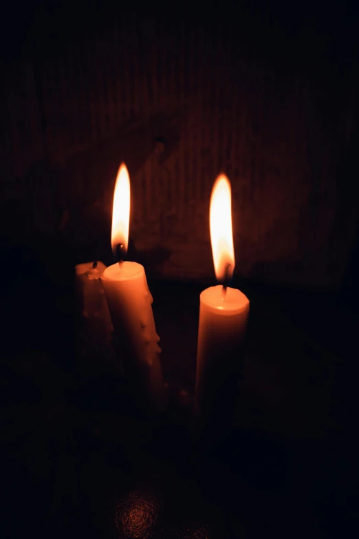 a couple of candles sitting on top of a table, an album cover, inspired by Elsa Bleda, pexels, spooky lighting, solemn, ignant, a wooden