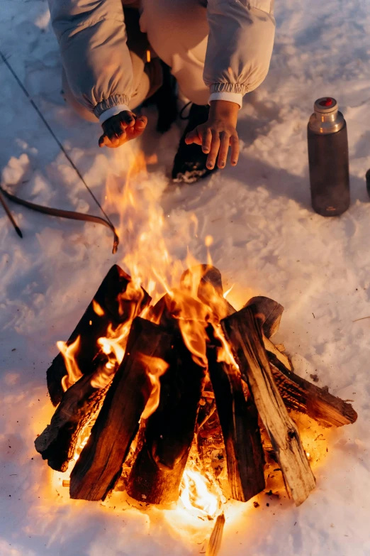 a man sitting next to a fire in the snow, holding a bottle of arak, slide show, nordic, multiple stories