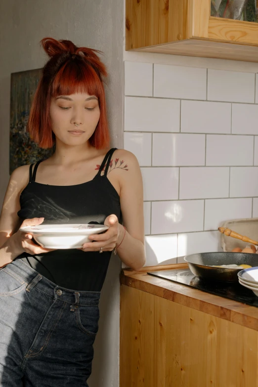 a woman standing in a kitchen holding a bowl, inspired by Elsa Bleda, pexels, red haired young woman, pan and plates, gif, sun yunjoo