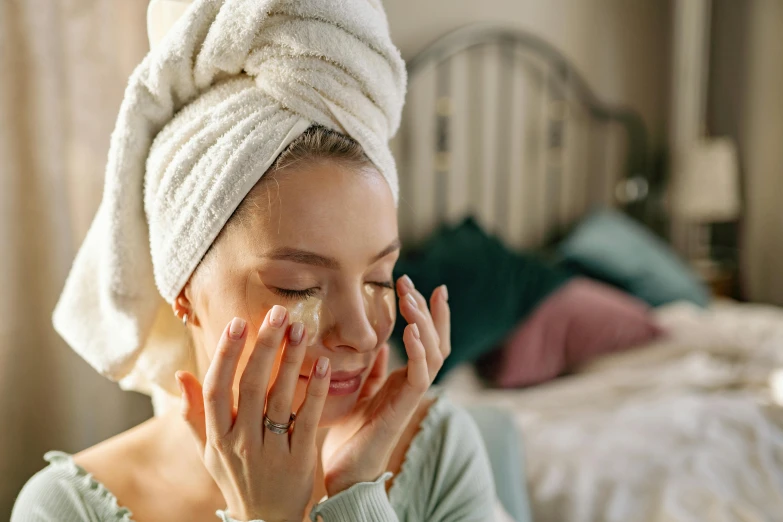 a woman with a towel on her head rubbing her face, a photo, by Julia Pishtar, trending on pexels, renaissance, in the bedroom at a sleepover, manuka, oils, natural make-up