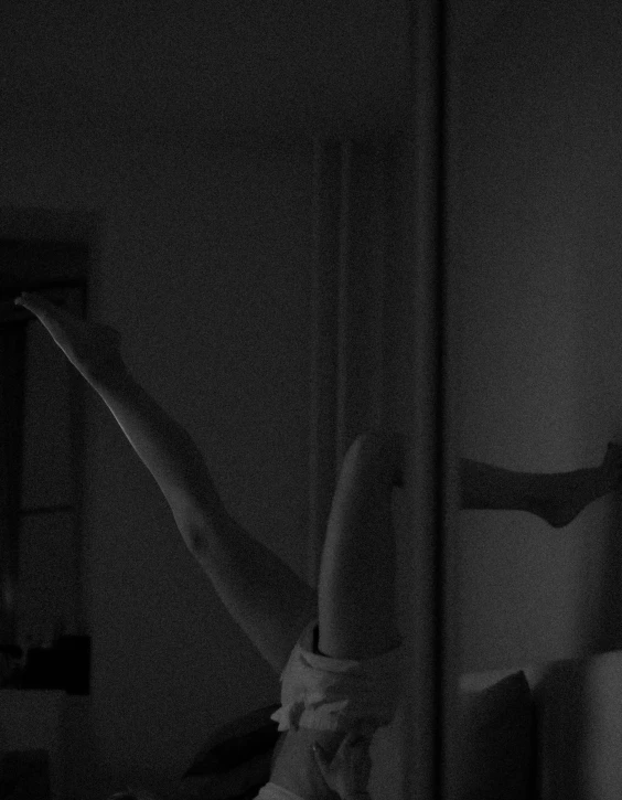 a woman doing a handstand in front of a mirror, a black and white photo, inspired by Nan Goldin, postminimalism, summer night, with arms up, dark aesthetic, detailed shot legs-up