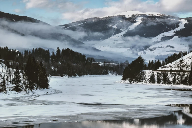 a body of water surrounded by snow covered mountains, a photo, inspired by Pierre Pellegrini, pexels contest winner, hurufiyya, river and trees and hills, ai weiwei and gregory crewdson, winter landscape outside, panorama