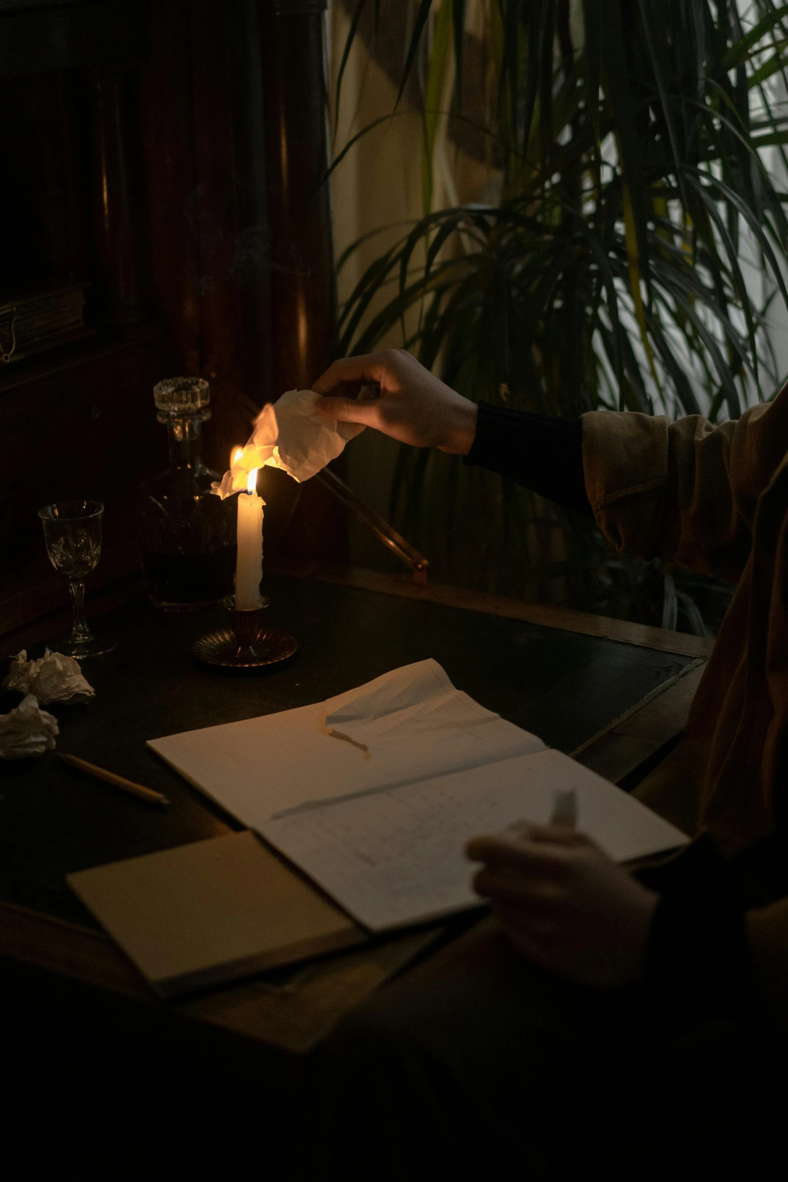 a person sitting at a table with a lit candle, pen and paper, gas lighting, ignant, action shot