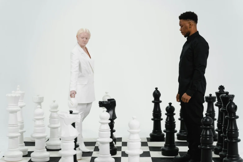 a man standing next to a woman on a chess board, an album cover, by Carey Morris, pexels contest winner, albino skin, white suit, musk ( 2 0 2 4 ), trending on dezeen