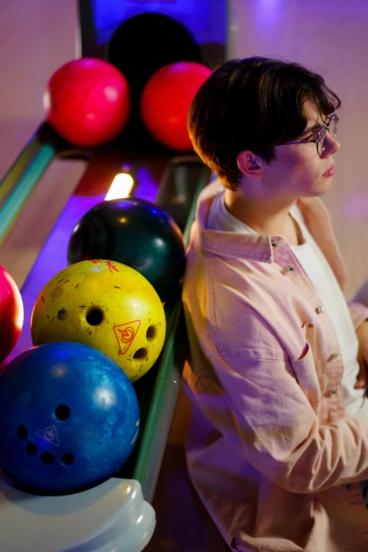 a woman sitting in front of a row of bowling balls, bisexual lighting, profile image, lee madgwick & liam wong, person in foreground