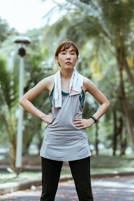 a woman standing on a skateboard in a park, a portrait, inspired by Ruth Jên, unsplash, happening, wearing a towel, wearing : tanktop, vietnamese woman, looking serious