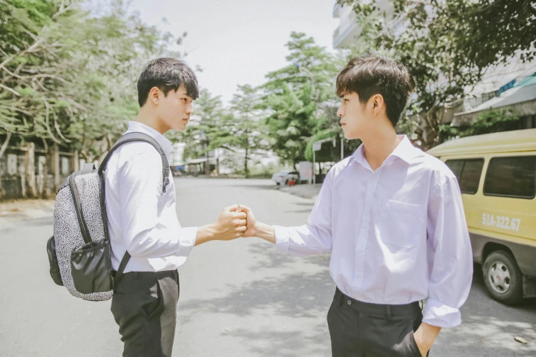 a couple of men standing next to each other on a street, by Jang Seung-eop, pexels contest winner, holding each other hands, standing in class, cute boys, ( ( theatrical ) )