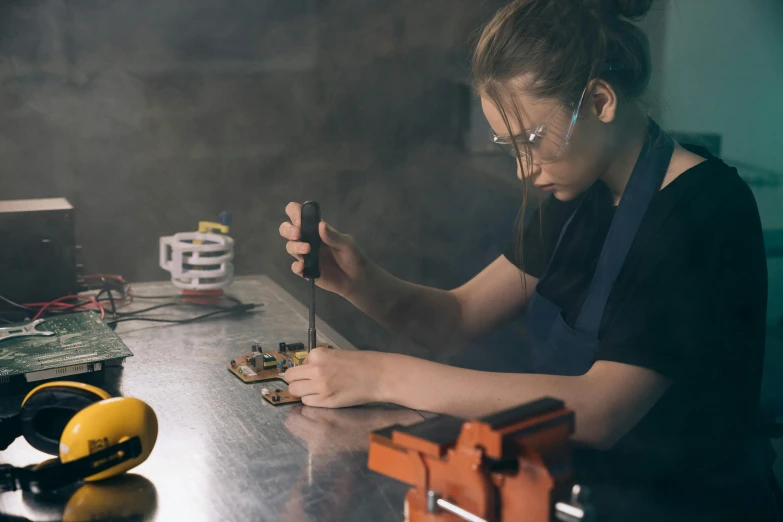 a woman is working on an electronic device, by Lee Loughridge, pexels contest winner, process art, a still life of a rusty robot, teenage engineering moad, welding torches for arms, 3 d print