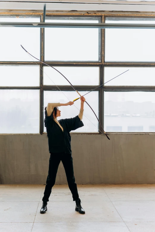 a woman is practicing archery in front of a large window, inspired by Fei Danxu, twigs, choreographed, julia hetta, commercially ready