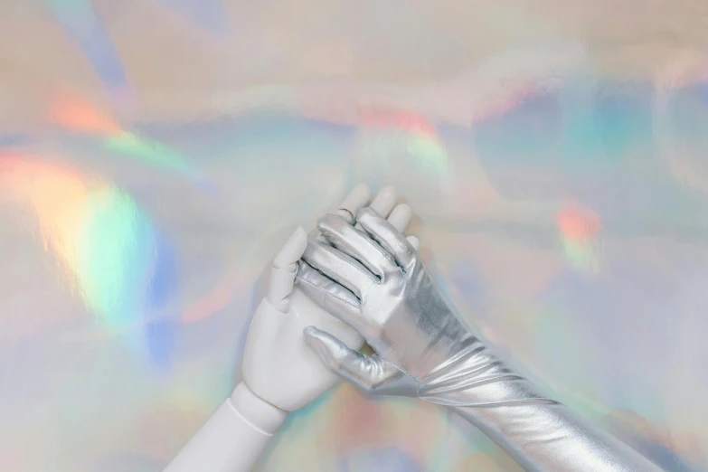 a close up of a person wearing silver gloves, inspired by Elsa Bleda, trending on pexels, holography, alternate album cover, white robot, holding each other hands, iridiscent fabric