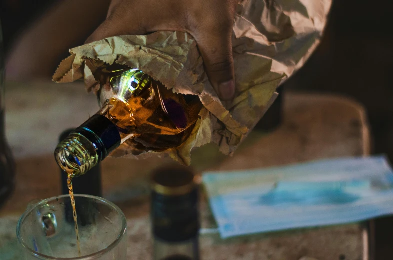 a bottle of alcohol being poured into a glass, pexels contest winner, process art, brown paper, foil, ayahuasca, whisky