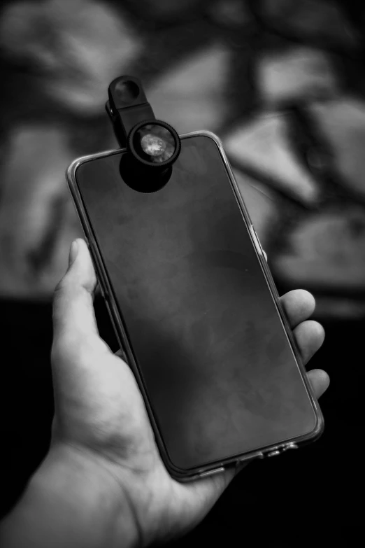 a person holding a cell phone in their hand, a black and white photo, by Adam Marczyński, pexels, photorealism, flashlight on, bodycam, cell cover style, magnifying glass