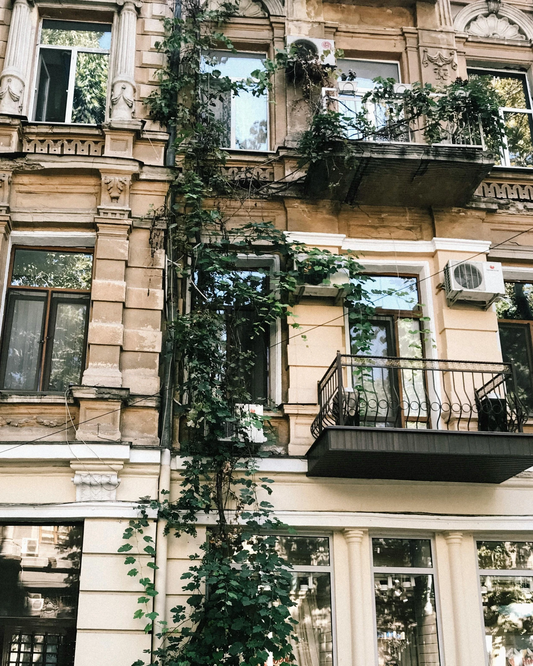 a tall building with lots of windows and balconies, by Emma Andijewska, unsplash contest winner, art nouveau, overgrown with lush vines, photo of putin, snapchat photo, cozy place