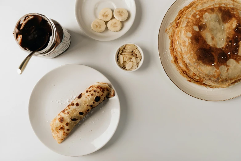 a pancake sitting on top of a white plate next to a cup of coffee, unsplash, maple syrup & hot fudge, banana, background image, manuka