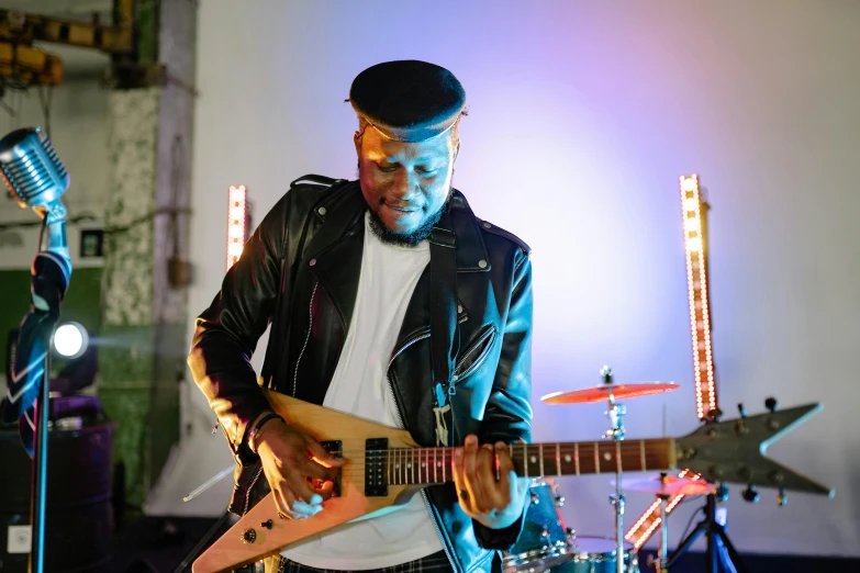 a man in a leather jacket playing a guitar, riyahd cassiem, warwick saint, lightening, profile image