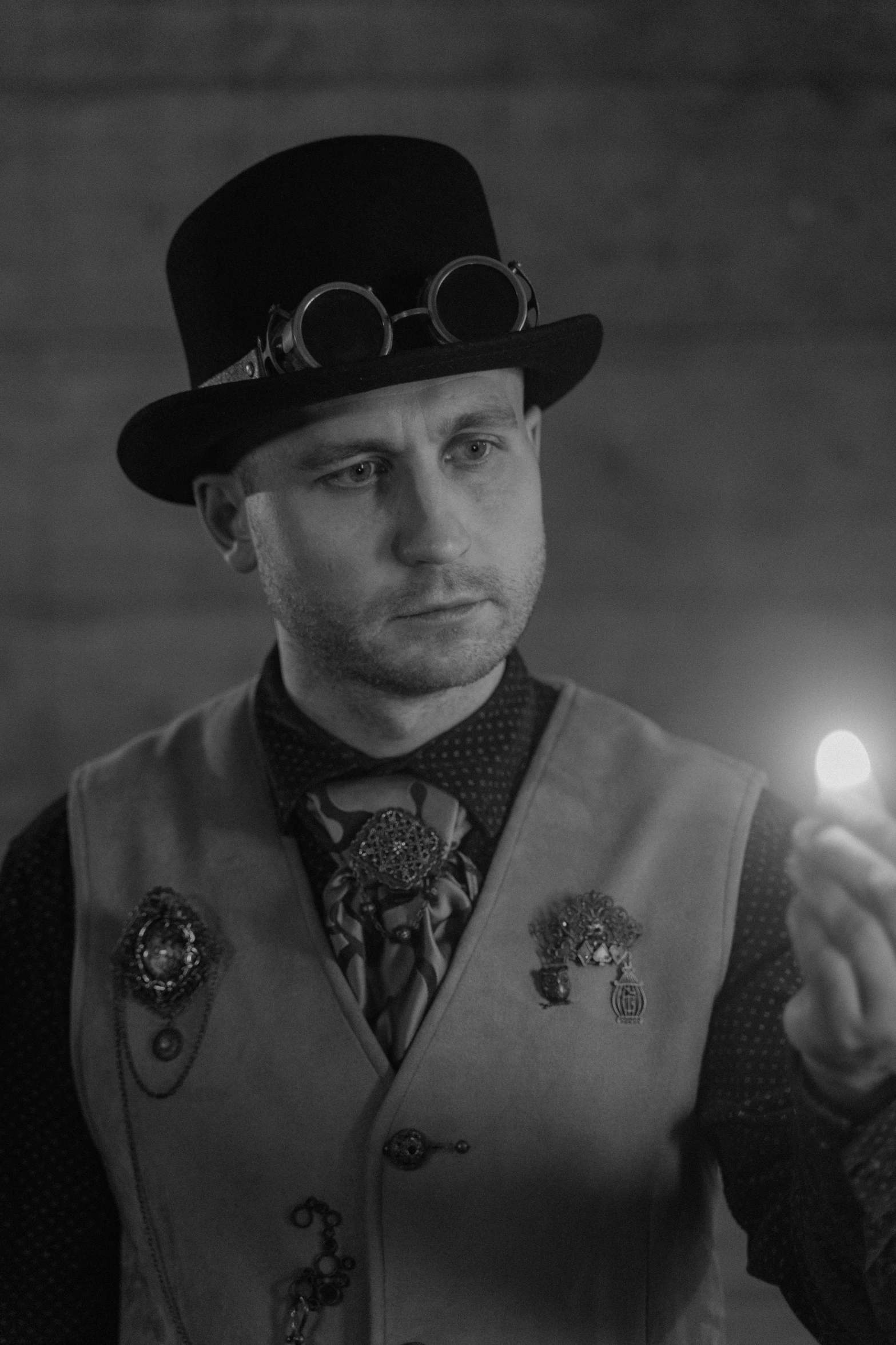 a man in a top hat holding a lit candle, a black and white photo, reddit, wearing steampunk attire, serious focussed look, (doctor), josh black