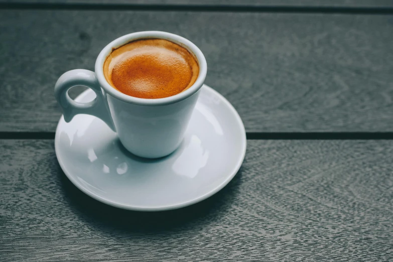 a cup of coffee sitting on top of a saucer, inspired by Géza Dósa, unsplash, medium format, no cropping, brown, tabletop