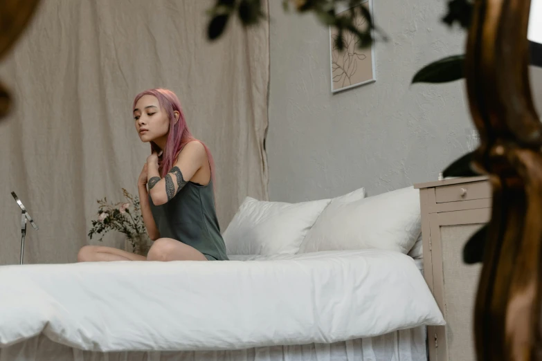 a woman with pink hair sitting on a bed, inspired by Elsa Bleda, trending on pexels, renaissance, peaceful environment, wearing a tank top and shorts, quiet and serene atmosphere, beds