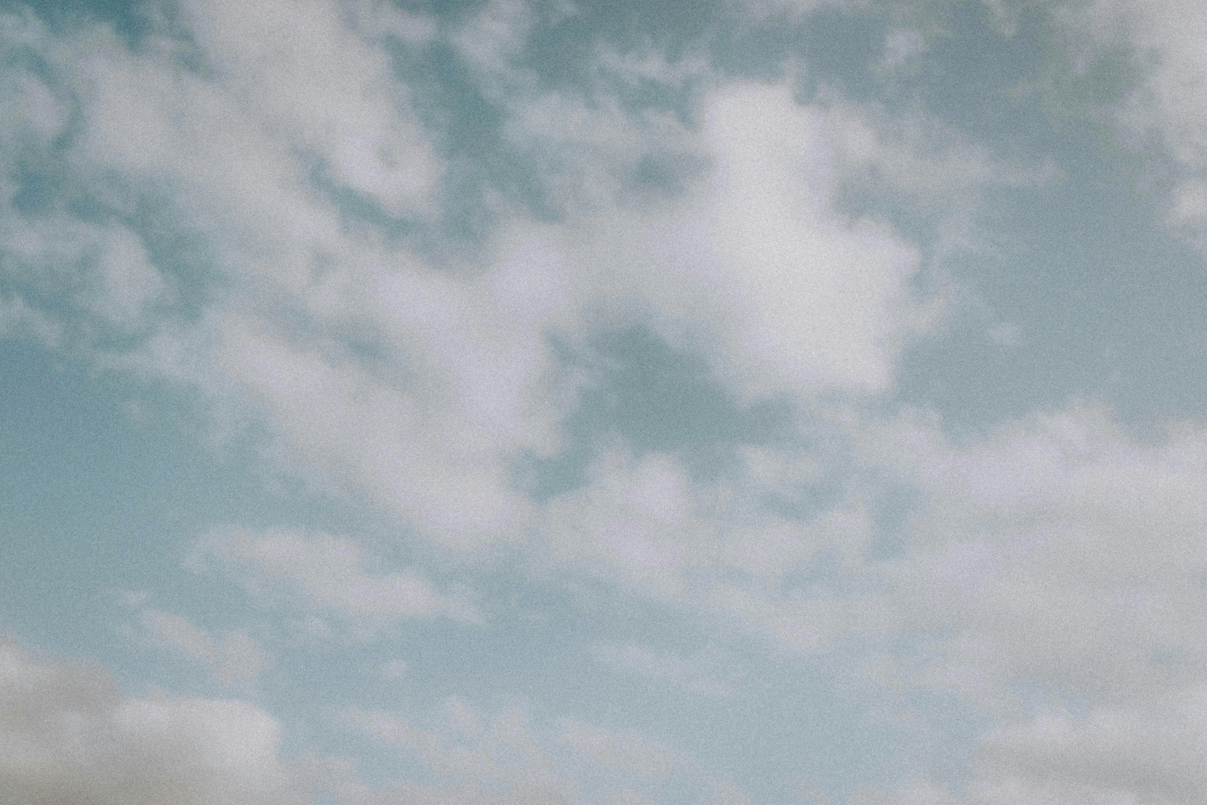 a man flying a kite on top of a lush green field, inspired by Elsa Bleda, pexels contest winner, minimalism, cotton clouds, white and pale blue toned, grainy footage, low-angle