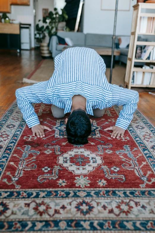 a man is doing a handstand on a rug, unsplash, kneeling in prayer, asian male, - 8, indoor picture