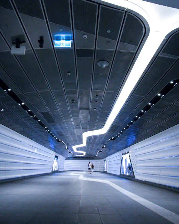 a couple of people that are standing in a tunnel, inspired by Zaha Hadid, unsplash contest winner, light and space, blue light accents, monorail station, street lighting, panoramic anamorphic