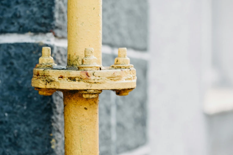 a yellow fire hydrant on the side of a building, unsplash, many rusty joints, background image, minimalist photo, dug stanat