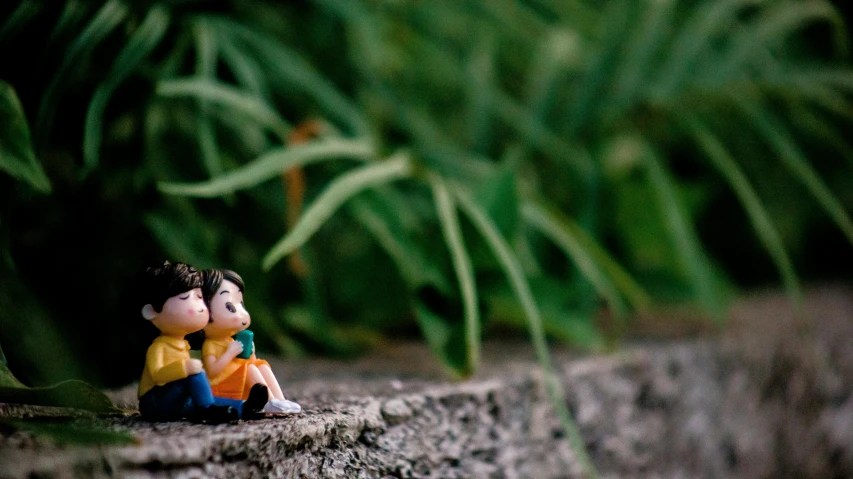 a small figurine sitting on top of a rock, lesbians, cute photograph, sitting in the garden, medium shot of two characters