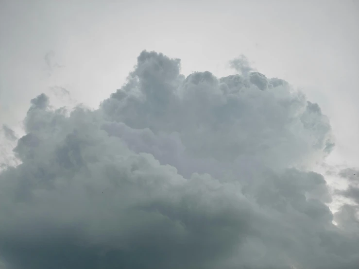 a group of people standing on top of a beach under a cloudy sky, an album cover, by Neil Blevins, pexels contest winner, romanticism, giant cumulonimbus cloud, closeup photograph, grey, 3/4 view from below