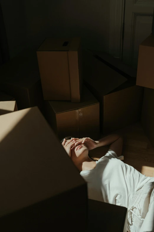 a woman laying on the floor surrounded by boxes, inspired by Elsa Bleda, pexels contest winner, renaissance, sad men, sun shining, gif, standing in a dimly lit room
