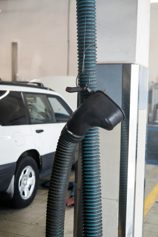 a car is parked at a gas station, plasticien, with pipes attached to it, dust in air, in a workshop, scientific photo