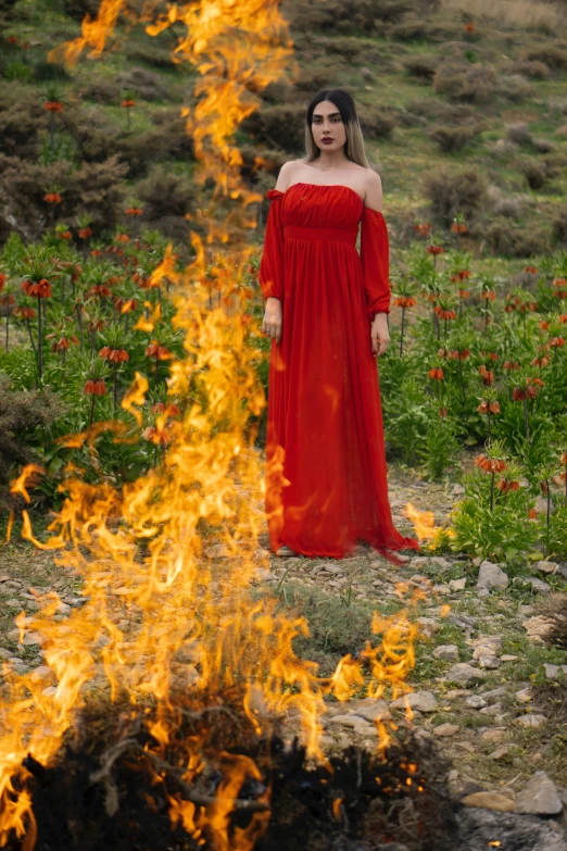 a woman in a red dress standing in front of a fire, an album cover, by Marina Abramović, pexels contest winner, renaissance, midsommar - t, detail shot, persephone in spring, fullbody view