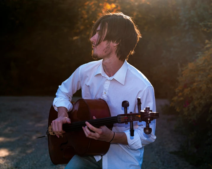 a man in a white shirt holding a guitar, an album cover, unsplash, romanticism, cello, avatar image, lachlan bailey, performing