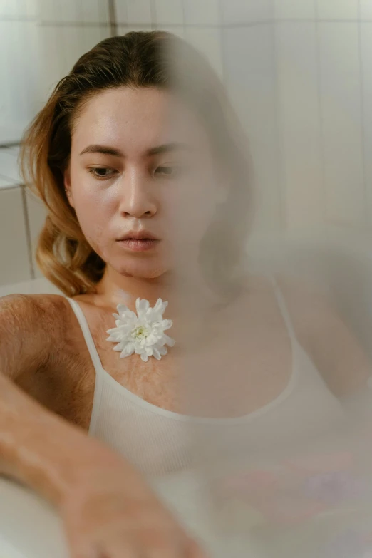 a woman sitting in a bathtub with a flower in her hair, inspired by Elsa Bleda, process art, wearing translucent sheet, chest hair, on a white table, full device
