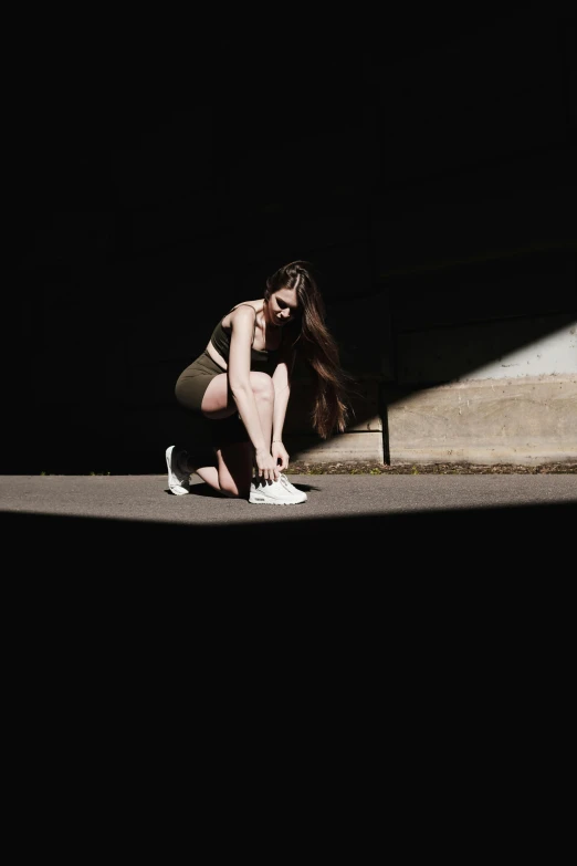 a woman sitting on the ground in the dark, inspired by Elsa Bleda, pexels contest winner, happening, wearing white sneakers, harsh sunlight, profile image, wearing a tanktop and skirt