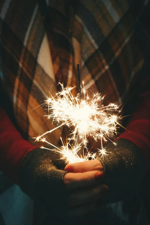 a person holding a sparkler in their hands, wearing festive clothing, metallic flecks, warm features, large)}]