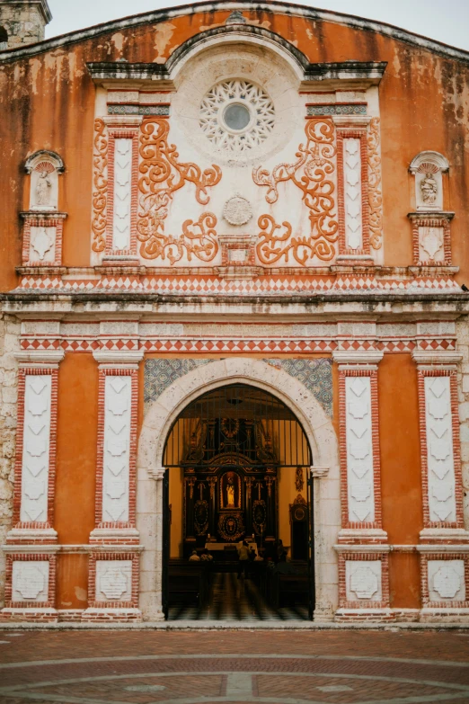 an orange and white building with a clock on it, an album cover, trending on unsplash, baroque, mexico, arched doorway, red fluid on walls of the church, intricate embroidery