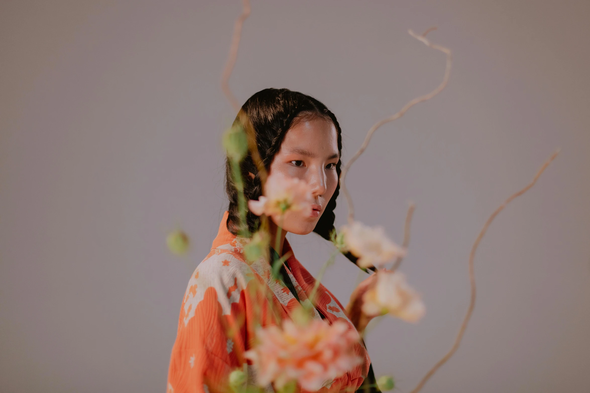 a woman standing in front of a vase of flowers, an album cover, inspired by Otake Chikuha, unsplash, hyperrealism, orange robe, sangsoo jeong, looking to the side off camera, ayami koj ima