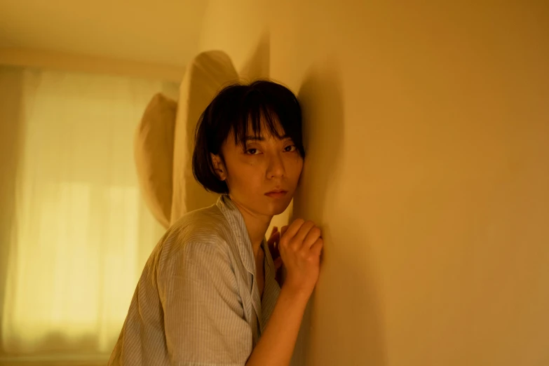 a woman leaning against a wall in a room, unsplash, shin hanga, movie still of a tired, yellow light, portrait 8 k, nanae kawahara