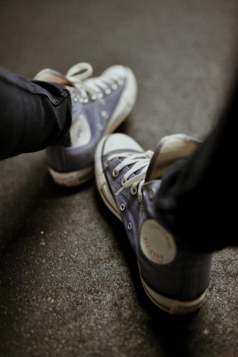 a person standing next to a pair of shoes, trending on pexels, converse, taken in the late 2010s, cool toned, high angle shot